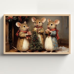 Puede incluir: Tres ratones marrones vestidos con ropa festiva se paran frente a un pequeño árbol de Navidad. Los ratones sostienen pequeños regalos y sonríen. El árbol está decorado con adornos rojos y dorados.