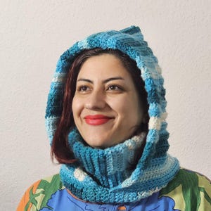 Könnte beinhalten: Ein gestrickter Kapuzen-Schal in Blau-Weiß mit passendem Halstuch. Der Schal ist aus weichem Garn gefertigt und hat eine bequeme Passform.