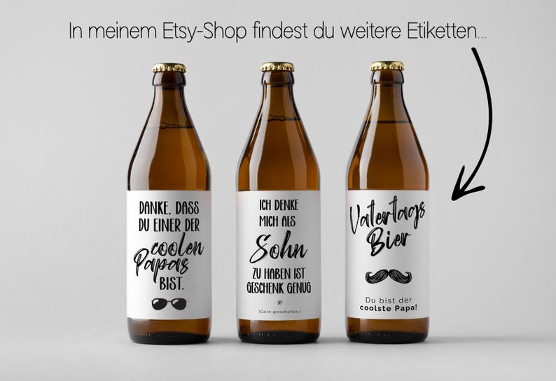 May include: Three brown beer bottles with white labels and gold caps. The labels have black text, including phrases like "coolest dad" and "Father's Day beer." The bottles are arranged against a light gray background.