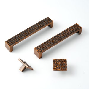 May include: Set of three antique bronze cabinet hardware pulls with a square, textured design. The set includes two long pulls and one small square knob.