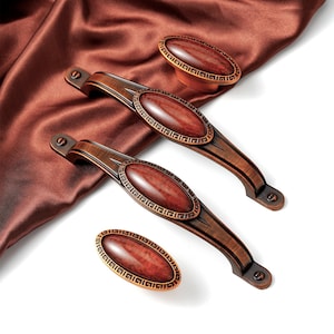 May include: Three antique-style cabinet knobs with ornate details. The knobs are oval-shaped with a red-brown finish and a decorative border.
