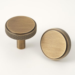 May include: Two antique brass cabinet knobs with a round, textured base and a smooth, circular top.