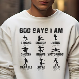 May include: A white sweatshirt with the text "GOD SAYS I AM" printed on the front. The text is surrounded by nine black silhouettes of people in different poses, each with a Bible verse underneath. The verses include: Psalm 18:15, 2 Corinthians 12:9, Psalm 139:13-14, 1 Thessalonians 5:18, Deuteronomy 31:6, Romans 8:37, Mark 10:27, John 15:13, and 1 John 5:14.