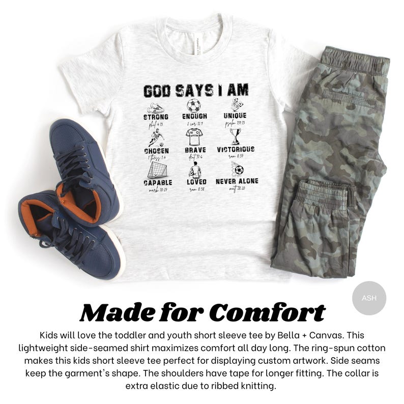 May include: A light gray t-shirt with the text "GOD SAYS I AM" and various inspirational words and images. The shirt is paired with gray camouflage pants and navy blue sneakers. The text "Made for Comfort" is also visible.