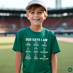May include: A young person wearing a Kelly green t-shirt with the words "GOD SAYS I AM" printed on the front. Below the text are the words "STRONG, ENOUGH, UNIQUE, CHOSEN, BRAVE, VICTORIOUS, CAPABLE, LOVED, NEVER ALONE". The person is wearing a white baseball cap.