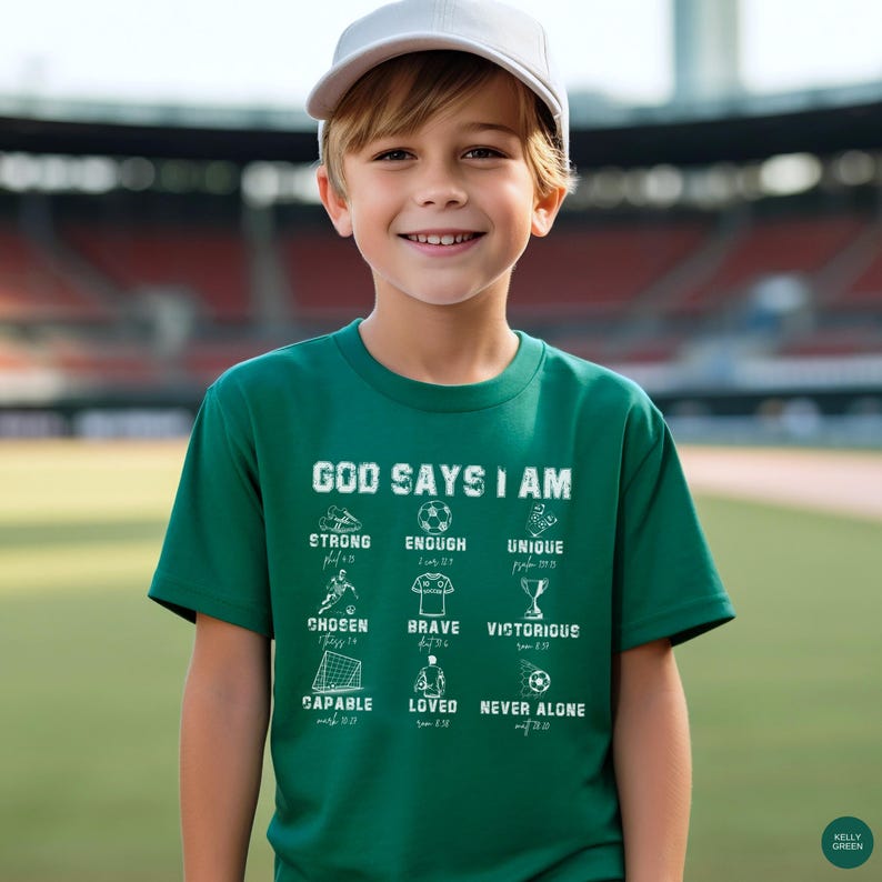 May include: A young person wearing a Kelly green t-shirt with the words "GOD SAYS I AM" printed on the front. Below the text are the words "STRONG, ENOUGH, UNIQUE, CHOSEN, BRAVE, VICTORIOUS, CAPABLE, LOVED, NEVER ALONE". The person is wearing a white baseball cap.