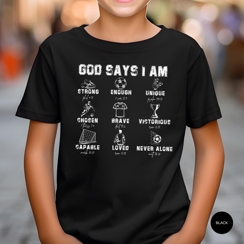 May include: Black t-shirt with white text and graphics. The text reads "GOD SAYS I AM" above various words like "STRONG", "ENOUGH", and "UNIQUE", each paired with a related image. The shirt also has the word "BLACK" in a circle.