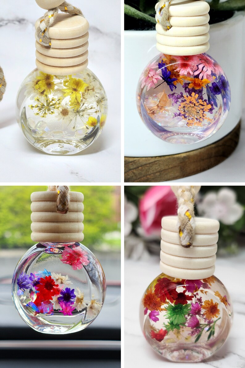 May include: Four clear glass car air fresheners filled with dried flowers. Each bottle has a wooden cap and a braided rope. The flowers are in shades of yellow, red, purple, and pink. The bottles are approximately 5 cm in diameter.