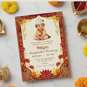 以下が含まれることがあります： アディティアのアンナプラシャンセレモニーの招待状。赤と金の縁取りに花柄とペイズリー柄のデザイン。赤ちゃんイラストが特徴。マリーゴールドの花、真鍮のランプ、装飾品に囲まれています。