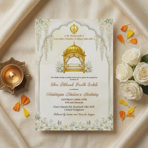 May include: An invitation card with gold accents and floral details. The card features text in English and another language, with a gold structure illustration. White roses and a lit candle are also visible.
