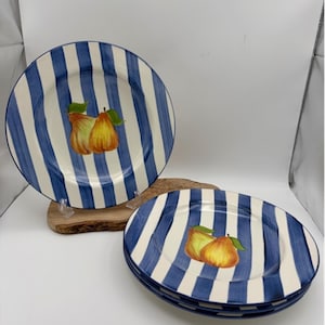 May include: Set of ceramic plates with blue and white vertical stripes. Each plate features a watercolor illustration of two pears with green leaves. The plates are round and have a slightly raised edge.