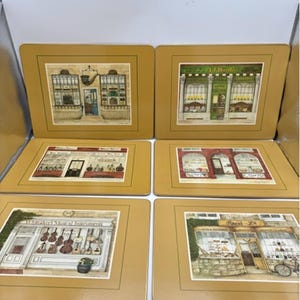 May include: A set of six rectangular placemats with a mustard yellow border. Each placemat features a detailed illustration of a different storefront, including a musical instrument shop labelled Whittaker's Musical Instruments and others.