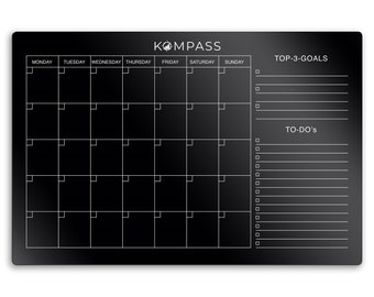 May include: A black dry-erase board with a weekly calendar, a section for top three goals, and a to-do list. The board has the text "KOMPASS" at the top.