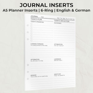 Könnte beinhalten: Weiße A5-Planereinlagen mit 6-Ring-Design. Die Einlagen haben Abschnitte für die Tagesplanung, einschließlich Prioritäten, Reflexion und Dankbarkeit. Der Text auf den Einlagen enthält "Journal", "Tagesplan" und "Tagesreflexion".
