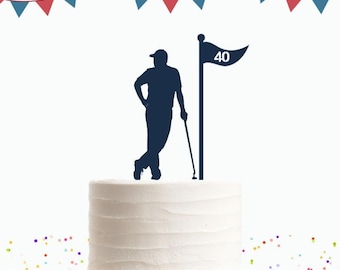 Peut inclure: Un gâteau blanc avec une silhouette bleue d'un golfeur debout à côté d'un drapeau de golf avec le numéro 40 dessus. Le gâteau est décoré de fanions rouge, blanc et bleu.