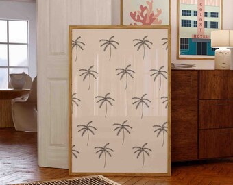 May include: A framed print featuring a repeating pattern of black palm trees on a pale pink background. The print is hanging on a wall in a room with a wooden floor and a wooden cabinet.