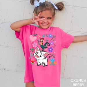 K&ouml;nnte beinhalten: Ein pinkfarbenes T-Shirt mit einem Cartoon-Bild eines Schweins und eines Hahns mit Blumen und Herzen. Das Shirt hat den Text "CRUNCH BERRY" unten.