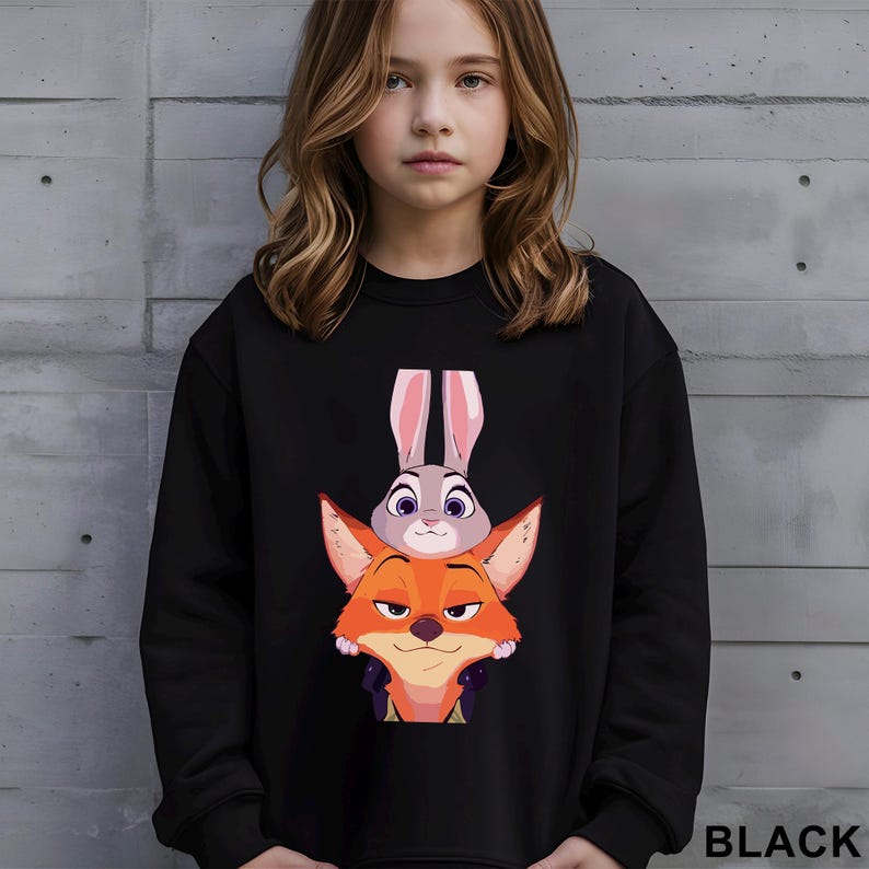 May include: Black sweatshirt featuring a graphic of Judy Hopps the bunny and Nick Wilde the fox from the animated movie Zootopia. The sweatshirt has a crew neck and long sleeves. The word "BLACK" is printed in white at the bottom right.