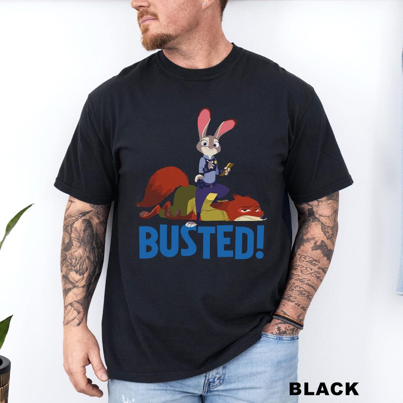 May include: Black t-shirt featuring a cartoon image of a rabbit police officer from Zootopia, standing on a red fox. The word "BUSTED!" is printed in blue below the image. The word "BLACK" is printed in white at the bottom.