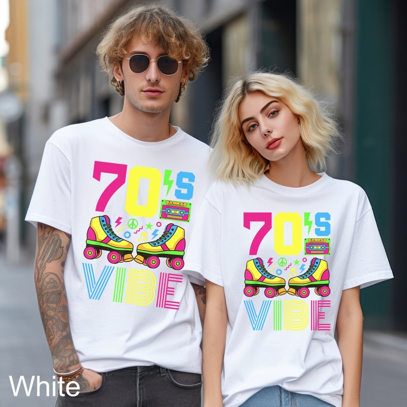 May include: Two white t-shirts with a retro 70s design. The shirts feature the text "70's Vibe" with a graphic of roller skates, lightning bolts, peace signs, and a cassette tape.