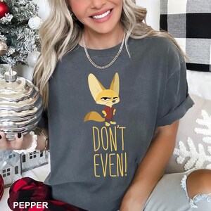 May include: Dark gray t-shirt featuring a cartoon fox with an angry expression, wearing a red vest. The text "DON'T EVEN!" is printed in yellow below the fox. The shirt is a comfortable, casual style.