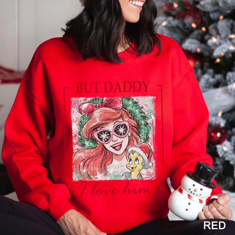 May include: Red sweatshirt featuring a graphic of a cartoon character with pink sunglasses and a small yellow character wearing a Santa hat. The text "BUT DADDY I love him" is printed on the front.