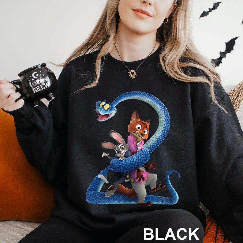 May include: Black sweatshirt featuring a colorful graphic of cartoon characters, including a fox, a rabbit, and a blue snake. The word "BLACK" is printed in white at the bottom. The sweatshirt is a crew neck style.