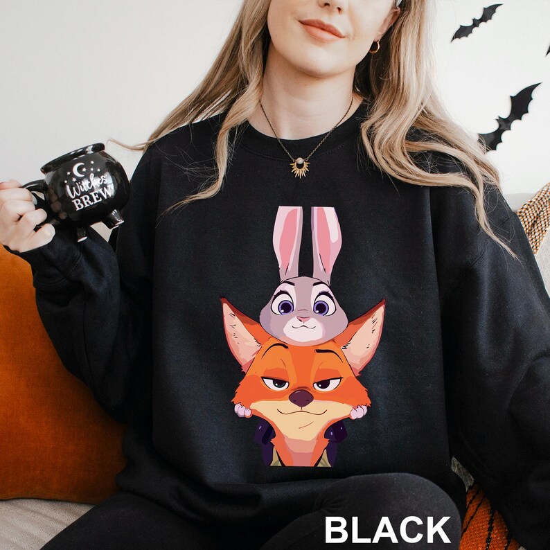 May include: Black sweatshirt featuring a cartoon image of a fox and a bunny. The fox is orange and the bunny is gray with pink ears. The word "BLACK" is printed in white at the bottom of the sweatshirt.
