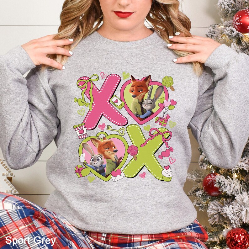 May include: A light gray sweatshirt featuring the text "XOX" in pink and green, with cartoon images of a fox and a rabbit inside hearts. The sweatshirt has long sleeves and the words "Sport Grey" are printed at the bottom.