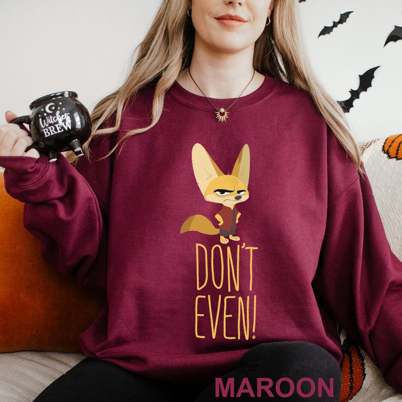 May include: Maroon sweatshirt with a cartoon fennec fox and the text "DON'T EVEN!". The fox wears a red vest. The sweatshirt is a solid maroon colour. The word "MAROON" is printed at the bottom of the sweatshirt.
