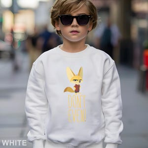 May include: White sweatshirt with a cartoon fox character and the text "DON'T EVEN!" in yellow. The fox wears a red vest. The sweatshirt is worn by a person wearing sunglasses.