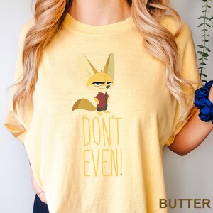 May include: Butter-colored t-shirt featuring a cartoon fennec fox with an annoyed expression, wearing a maroon vest and dark pants. The text "DON'T EVEN!" is printed below the fox in yellow. The word "BUTTER" is printed at the bottom right.
