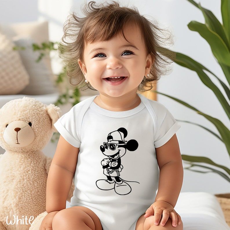 Może przedstawiać: Biały śpioszek dla niemowlęcia z czarno-białą ilustracją Myszki Miki w okularach przeciwsłonecznych i czapce z daszkiem.