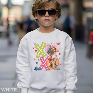 May include: White sweatshirt featuring a colorful graphic of the characters from the movie Zootopia. The design includes the letters "XO" with heart-shaped images of the characters. The word "WHITE" is printed at the bottom.