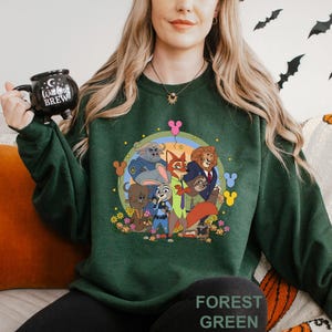 May include: Dark green sweatshirt with a cartoon graphic of animal characters, including a fox and a lion. The design is set against a circular background with flowers and balloons. The text "FOREST GREEN" is printed at the bottom.