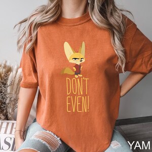 May include: Burnt orange t-shirt featuring a cartoon fox with an angry expression. The fox is wearing a red shirt. The text "DON'T EVEN!" is printed in yellow below the fox. The shirt is a comfortable, casual style.