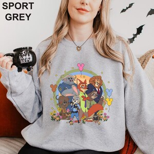 May include: Sport grey sweatshirt with a cartoon graphic of animal characters. The design includes a fox, lion, bunny, and other animals in a circular design with flowers and balloons. The words "SPORT GREY" are printed at the top.