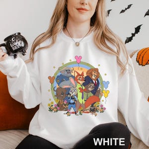 May include: White sweatshirt with a cartoon graphic of animal characters. The design includes a fox, lion, bunny, and other animals, surrounded by flowers and stars. The word "WHITE" is printed at the bottom of the sweatshirt.