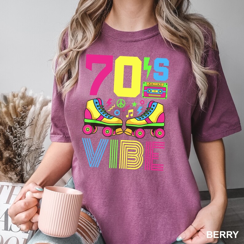 May include: A purple t-shirt with the text "70's Vibe" in colorful letters. The design includes a pair of roller skates, a cassette tape, and other 70s-inspired graphics.