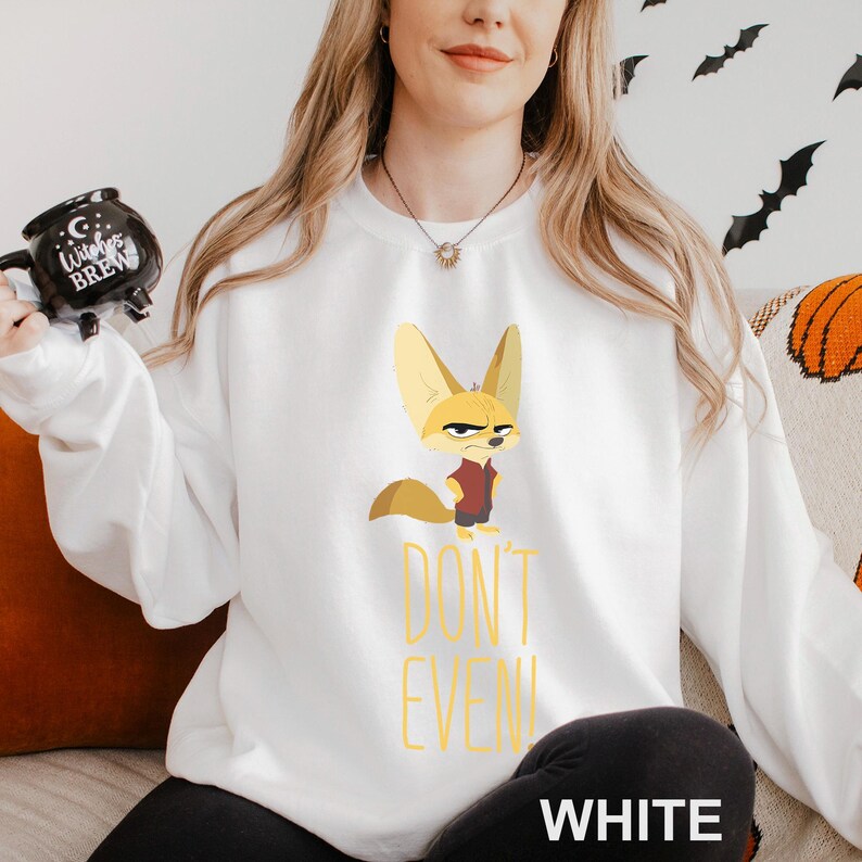 May include: White sweatshirt with a cartoon fennec fox in a red shirt and a stern expression. The text "DON'T EVEN!" is printed in yellow below the fox. The word "WHITE" is printed at the bottom of the sweatshirt.
