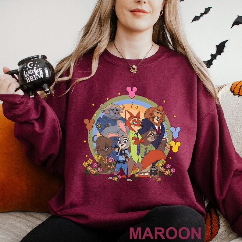 May include: Maroon crew neck sweatshirt with a colourful graphic of cartoon animal characters inside a rainbow circle. The graphic includes a fox, lion, bunny, and other characters. The word "MAROON" is printed at the bottom.