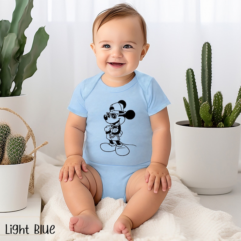 Może przedstawiać: Dziecko w jasnoniebieskim body z czarno-białą ilustracją Myszki Miki w okularach przeciwsłonecznych i czapce.