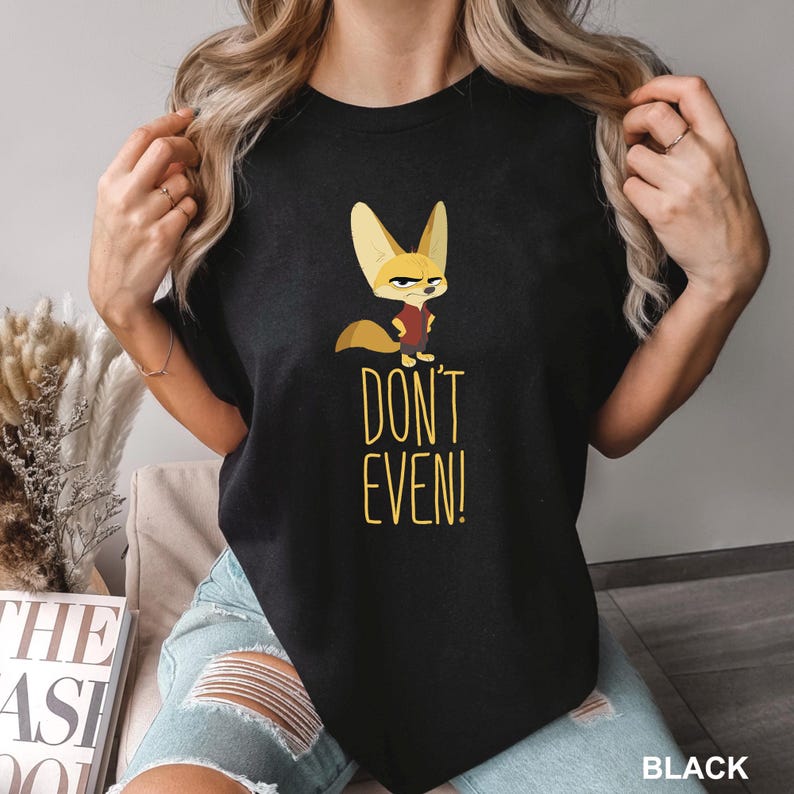 May include: Black t-shirt featuring a cartoon fox with large ears and a stern expression, wearing a red vest. The text "DON'T EVEN!" is printed in yellow below the fox. The word "BLACK" is printed at the bottom right.