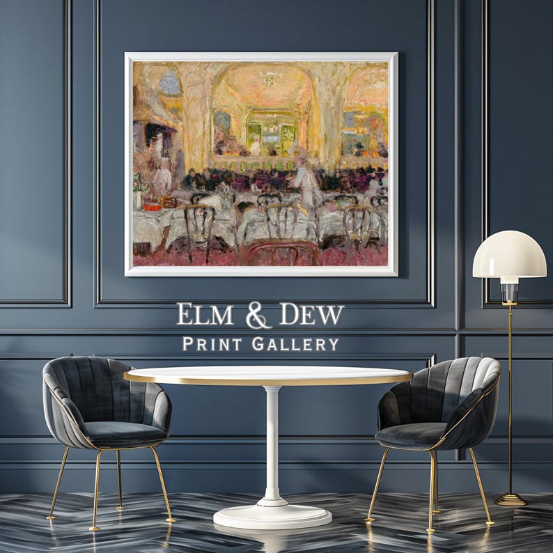 May include: A framed print of an impressionist painting depicting a restaurant interior with patrons and servers. The print is displayed above a white table and two gray velvet chairs with gold legs. The text "ELM & DEW PRINT GALLERY" is below the print.