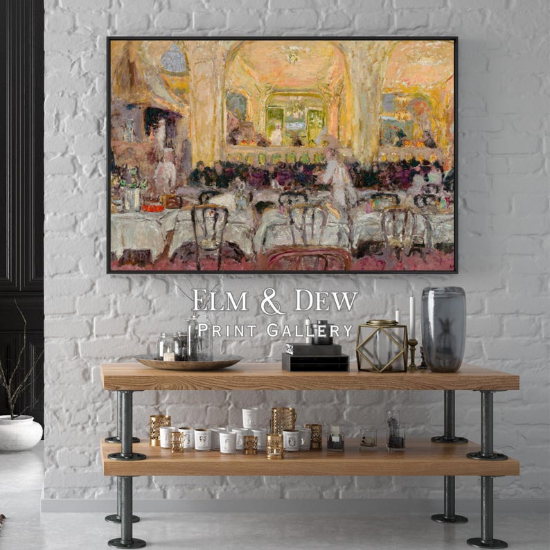 May include: A framed painting depicting a restaurant scene with tables and chairs, hanging above a wooden shelf. The shelf displays decorative items, including candles, a glass vase, and a metal tray. The text "ELM & DEW PRINT GALLERY" is below the painting.