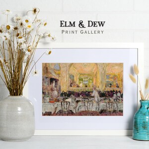 May include: A framed print of an impressionist painting depicting a restaurant scene with tables, chairs, and figures. The artwork is in a white frame, with the text "ELM & DEW PRINT GALLERY" above it. The image is displayed with a vase of dried flowers and a turquoise vase.