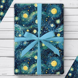 May include: A rectangular gift wrapped in paper featuring a dark blue, teal, and yellow swirling starry night pattern. The package is tied with a light blue satin ribbon that is knotted in a bow at the center of the top surface of the gift.