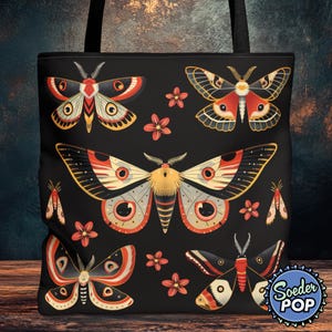 May include: Black tote bag with a colorful design featuring various moths and flowers. The moths have red, white, and black wings with intricate details. The flowers are red and white.