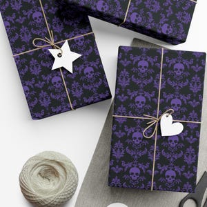 May include: Wrapped gifts featuring a black and purple skull damask design. The presents are tied with twine and have white star and heart-shaped tags. A ball of twine and scissors are also visible.