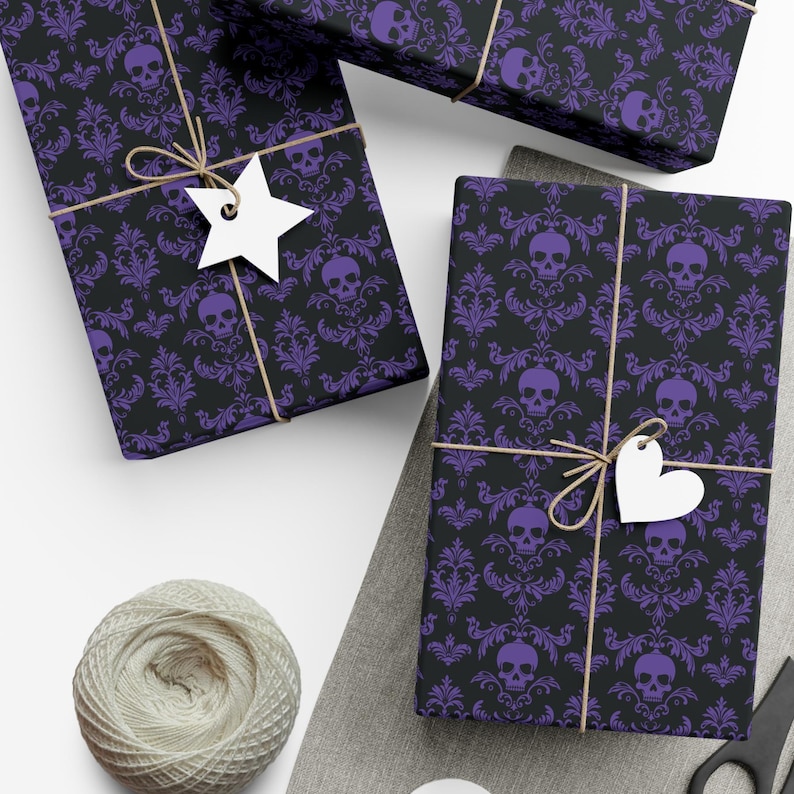 May include: Wrapped gifts featuring a black and purple skull damask design. The presents are tied with twine and have white star and heart-shaped tags. A ball of twine and scissors are also visible.